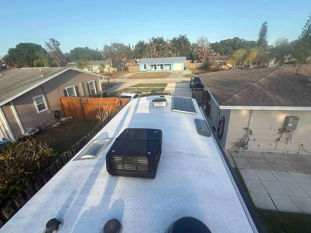 Coast to Coast RV technician replacing a rooftop AC unit on an RV at a Florida campground